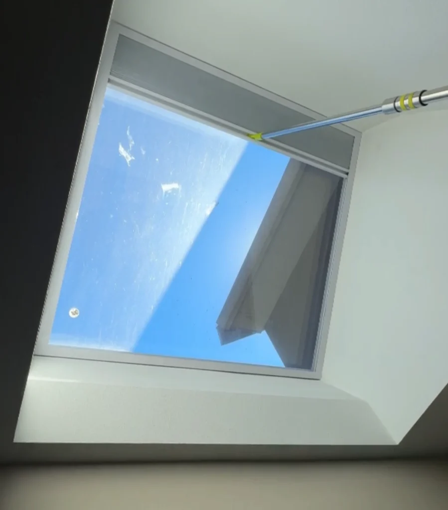 Cleaning a skylight with a pole.
