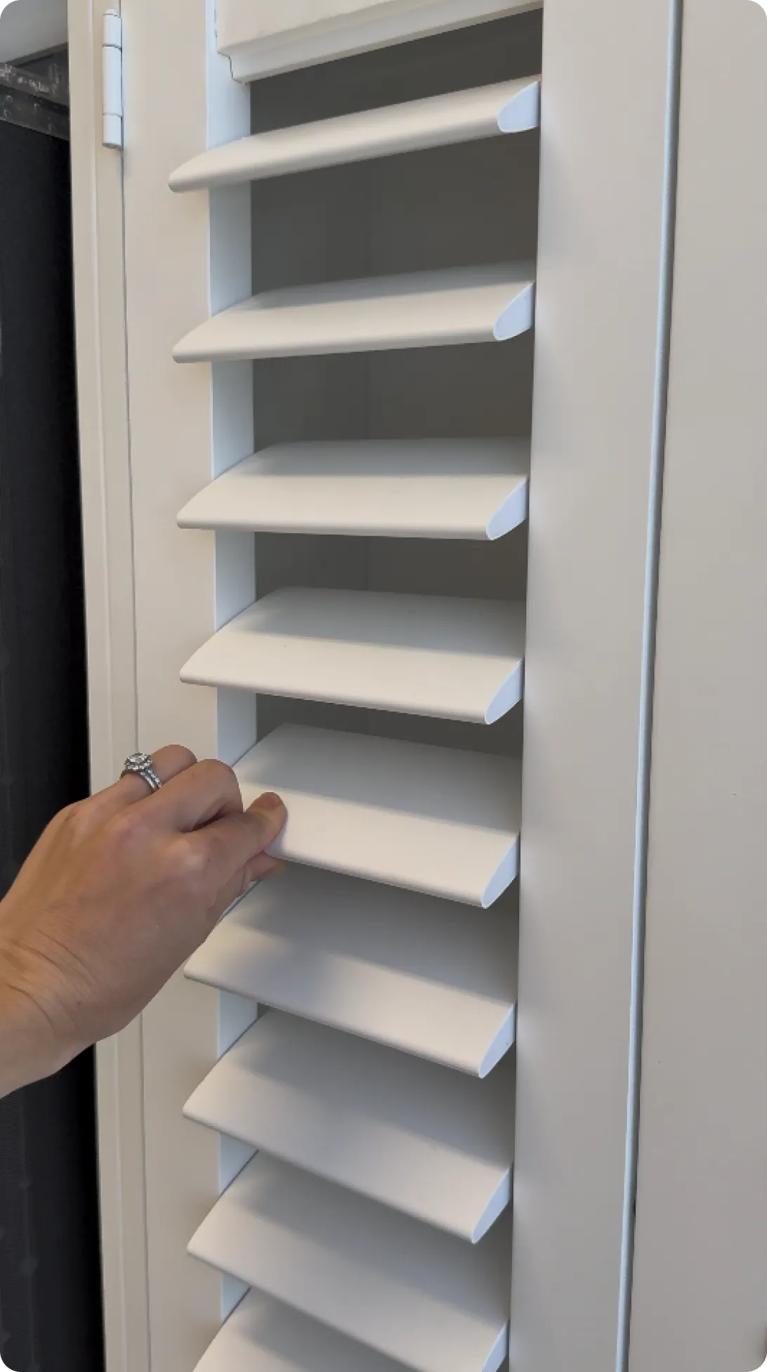 Hand adjusting white window shutters